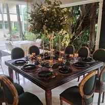 Mesa con vajilla oscura y arreglos florales